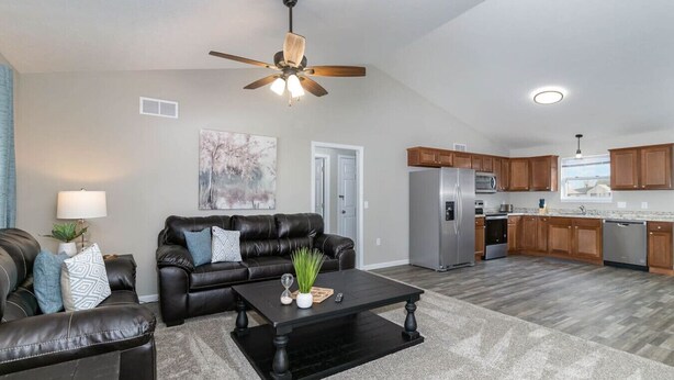 A modern living room with a leather sofa, a coffee table, and a ceiling fan. - BRAND NEW home among the Nook in Hamilton, OH (Hamilton)