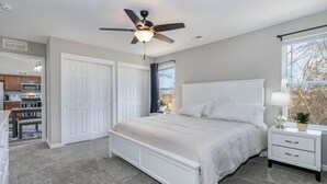 A bedroom with a bed, a nightstand, a ceiling fan, and a window. - BRAND NEW home among the Nook in Hamilton, OH (Hamilton)