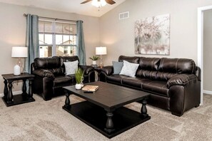 A living room with a sofa, coffee table, two side tables, and a painting on the wall.