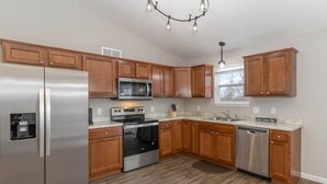 A kitchen with wooden cabinets, stainless steel appliances, a microwave, oven, dishwasher, and a water dispenser. - BRAND NEW Home away from Home among the Nook (Hamilton)