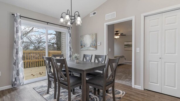 A dining area with a table and chairs, a chandelier, a painting on the wall, and a door leading to another room. - BRAND NEW Home away from Home among the Nook (Hamilton)