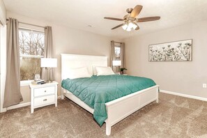 A bedroom with a bed, nightstands, a ceiling fan, and a window with curtains. - 16 E Persimmons · Quietly nestled among the Nook (Hamilton)