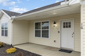 A single-story house with a front door, two windows, a small porch, and a number '16' on the right side. - 16 E Persimmons · Quietly nestled among the Nook (Hamilton)