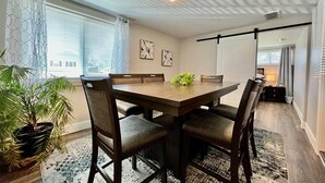 A dining area with a table and chairs, a potted plant, and a ceiling light fixture.