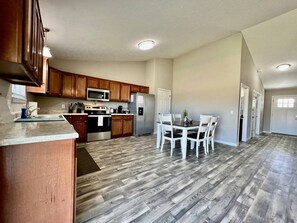 Una cocina amplia con armarios de madera, un comedor con sillas blancas y una isla central.