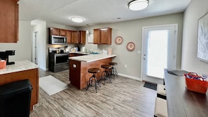 A modern kitchen with wooden cabinets, a central island with stools, a microwave, and an oven. - 430 Ridgelawn · Brand New Home Walking distance to Spooky Nook (Hamilton)
