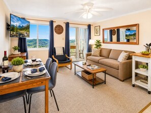A living room with a sofa, a dining table set for two, a TV, and a view of the outdoors. - ML258 Slope Side Getaway with Deck (Snowshoe)
