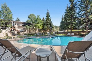 A pool area with lounge chairs, a small table, and a fenced pool. - Ridgepoint Townhome 142 - 3.5 Bedroom plus Loft Residence (Avon)
