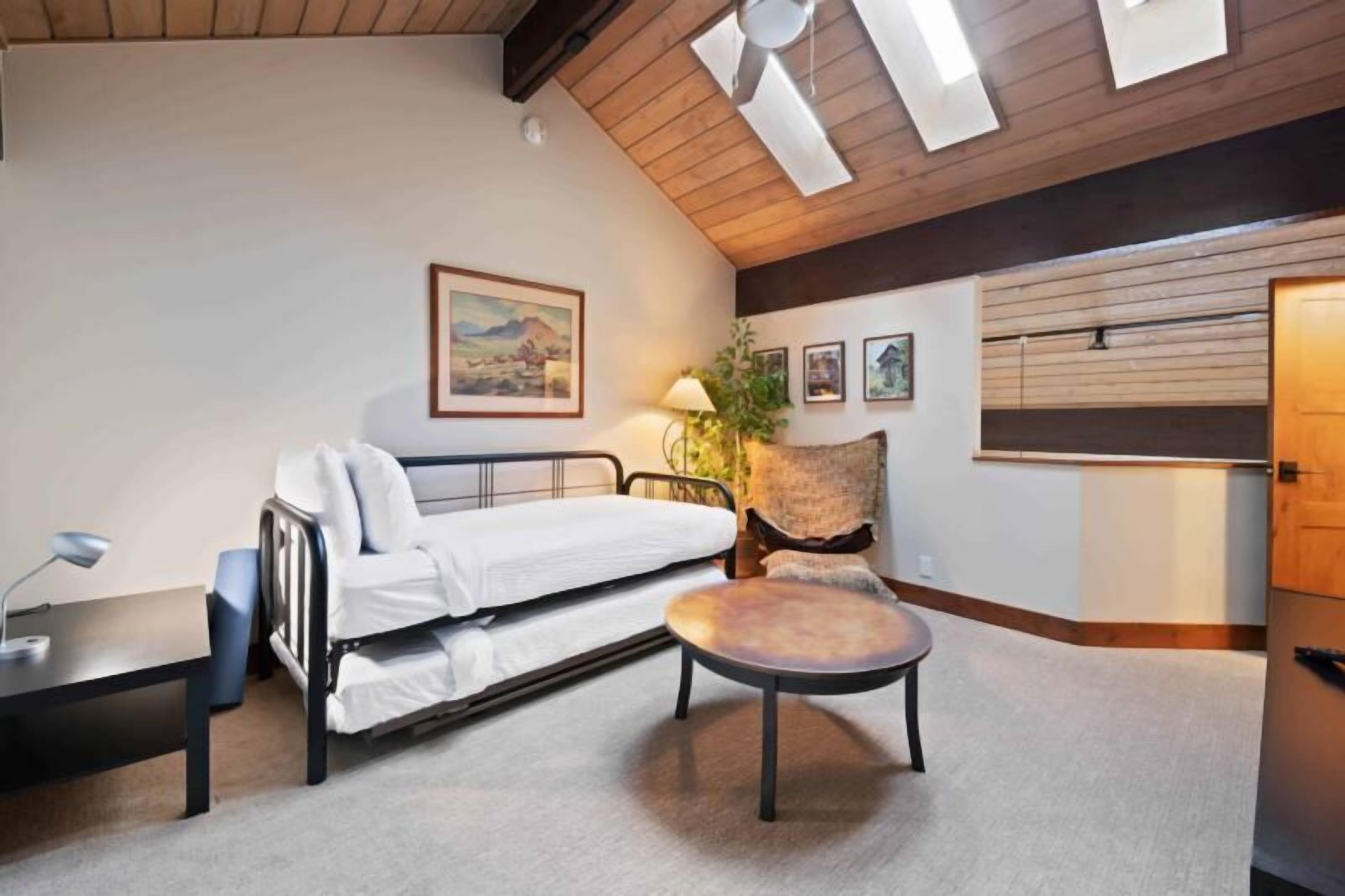A bedroom with a bed, a chair, a desk, and a lamp.