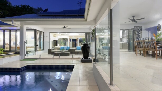 A modern house with a swimming pool, glass doors, and a dining area. - Bella Beach House | Port Douglas (PORT DOUGLAS)