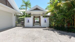 A modern house with a white facade, a garage, and a gated entrance. - Bella Beach House | Port Douglas (PORT DOUGLAS)