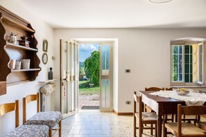 Ein Essbereich mit Tisch, Stühlen und Blick auf einen Garten durch eine offene Tür.