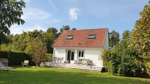 A single-story house with a red-tiled roof, a small porch with outdoor seating, and a well-maintained lawn. - Holiday Home 'Gite En Baie De Somme' with Private Terrace, Private Garden and Wi-Fi (Saint-Quentin-en-Tourmont)