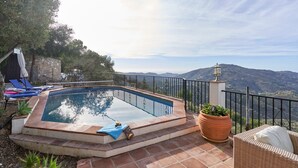 A swimming pool with a view of the mountains, a wicker chair, and a potted plant. - Holiday Home 'Casa Oliana' with Sea View, Pool, Garden & Wi-Fi (Competa)