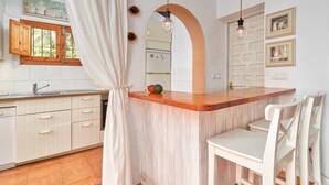 A kitchen with a wooden island, white cabinets, a window with wooden shutters, and a hanging light fixture. - Holiday Home 'Casa Oliana' with Sea View, Pool, Garden & Wi-Fi (Competa)
