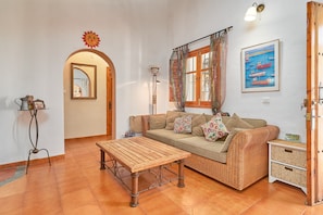 A living room with a sofa, a wooden table, a lamp, a framed picture, and a door.