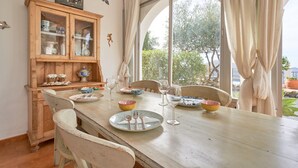 A dining area with a wooden table, chairs, and a cabinet with glass doors. - Holiday Home 'Casa Oliana' with Sea View, Pool, Garden & Wi-Fi (Competa)