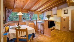 Ein Holzinterieur mit Esstisch, Stühlen, einem Fernseher und einer Küchenzeile.