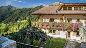 Eine Chalet mit Balkon, Steinwänden und einem Bergpanorama im Hintergrund.