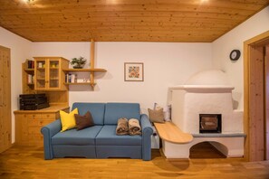 A cozy room with a blue sofa, wooden cabinet, and a wood-burning stove.
