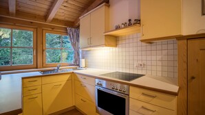 Eine Küche mit Holzschränken, einem Herd und einem Fenster mit Vorhängen.