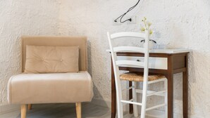 Une pièce avec un canapé beige, une chaise blanche, un bureau en bois et un mur blanc à texture.