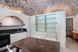 A kitchen with a stone ceiling, white cabinetry, and a wooden table.