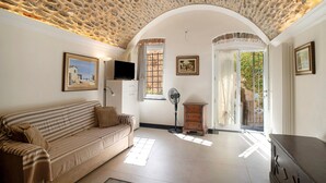 A room with a stone ceiling, a sofa, a TV, a fan, and a door leading outside. - Holiday Apartment 'La Credenza, Borgo Dei Pescatori' with Wi-Fi (Cervo)