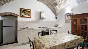A kitchen with a stone ceiling, a refrigerator, a stove, and a dining table with chairs.