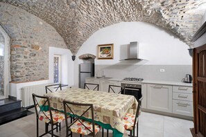 A kitchen with stone walls, a table with floral chairs, and a stove.