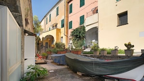 A narrow alley with boats covered on a wooden stand, potted plants, and buildings with balconies.