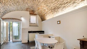 Una cocina con techo de piedra, armarios blancos y un comedor con sillas blancas.