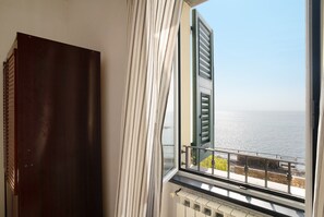 Une chambre avec vue sur la mer, un radiateur et une porte en bois sombre.