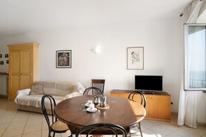 Un salon avec une table ronde en bois, un canapé, un téléviseur et un meuble.