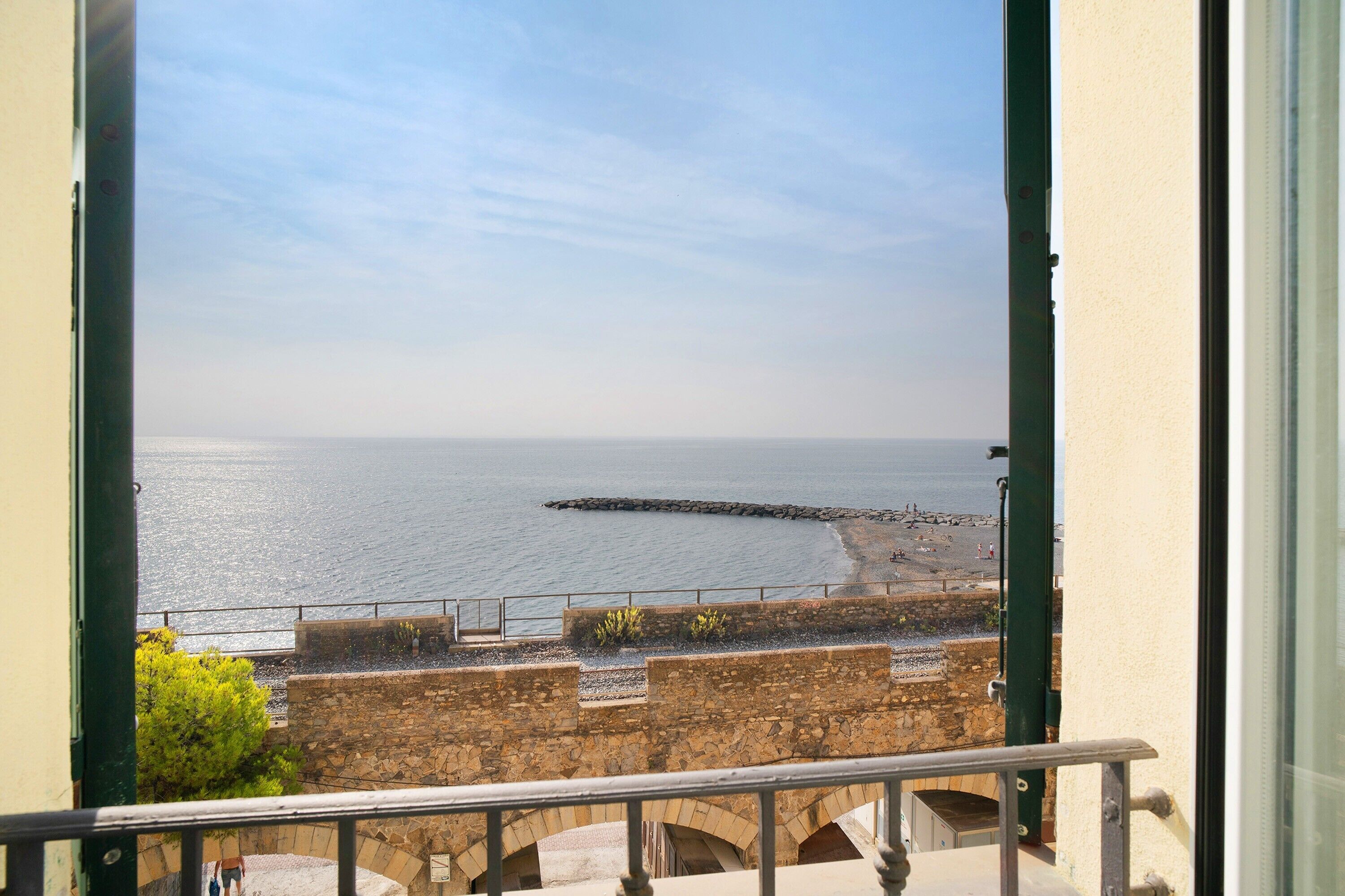 A balcony with a stone wall and a view of the sea.