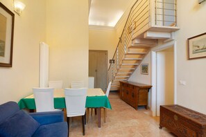 Comedor con mesa lista para cuatro personas, una escalera y un armario de madera.