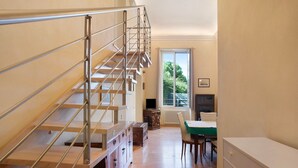 A staircase with metal railings, a wooden cabinet, a table with a green tablecloth, and a window with a view of greenery. - Ferrovia, Borgo Dei Pescatori Apartment with Sea View and Wi-Fi (Cervo)
