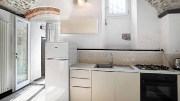 Een koelkast, een oven, een kookplaat, kookgerei, borden en bestek