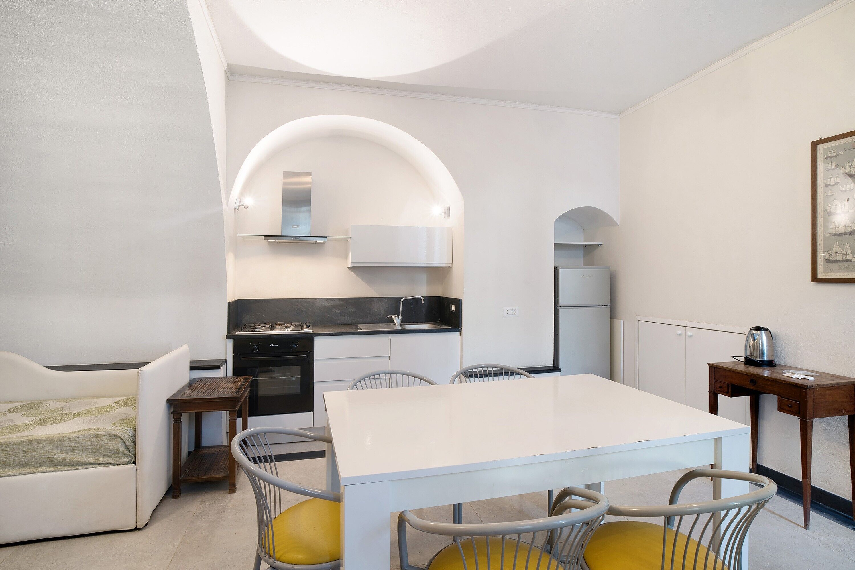 A compact kitchen with white cabinetry, a dining table, and a sofa.