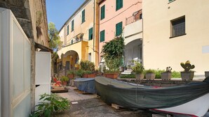 A narrow alley with boats covered on a wooden stand, potted plants, and buildings with balconies. - Buddha, Borgo Dei Pescatori Apartment with Wi-Fi (Cervo)