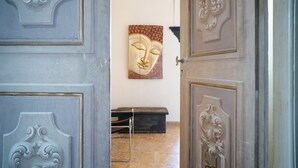 A room with a door leading to a hallway, a bench, and a wall with a Buddha statue. - Buddha, Borgo Dei Pescatori Apartment with Wi-Fi (Cervo)