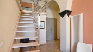 A staircase with a metal railing, a radiator, and a door in a hallway. - Buddha, Borgo Dei Pescatori Apartment with Wi-Fi (Cervo)