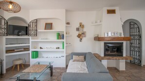 Ein Wohnzimmer mit Sofa, Fernseher, Regalen, Kamin und Wanddekoration.