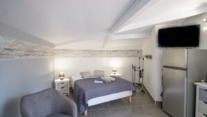 Ein Schlafzimmer mit Bett, Nachttischen, einem Sessel, einem Fernseher und einem Kühlschrank.