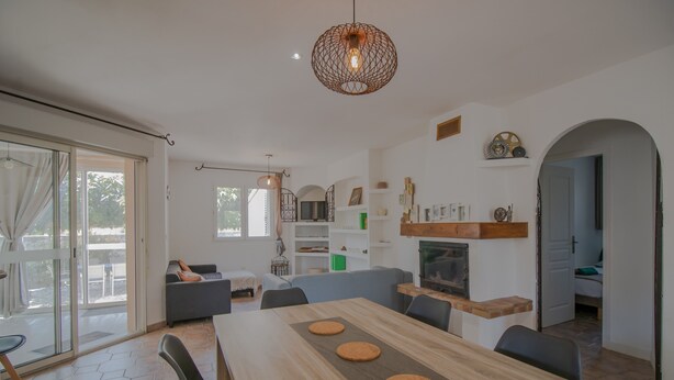 A modern living room with a dining table, sofas, and a fireplace.