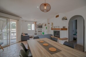 A modern living room with a dining table, sofas, and a fireplace.