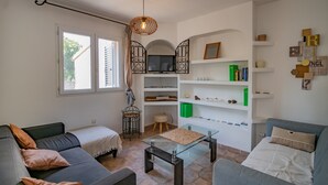 A modern living room with a sofa, a glass coffee table, a TV, and a bookshelf.
