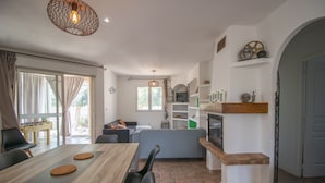 A modern kitchen with a dining area, wooden table, and a view of the outdoors.