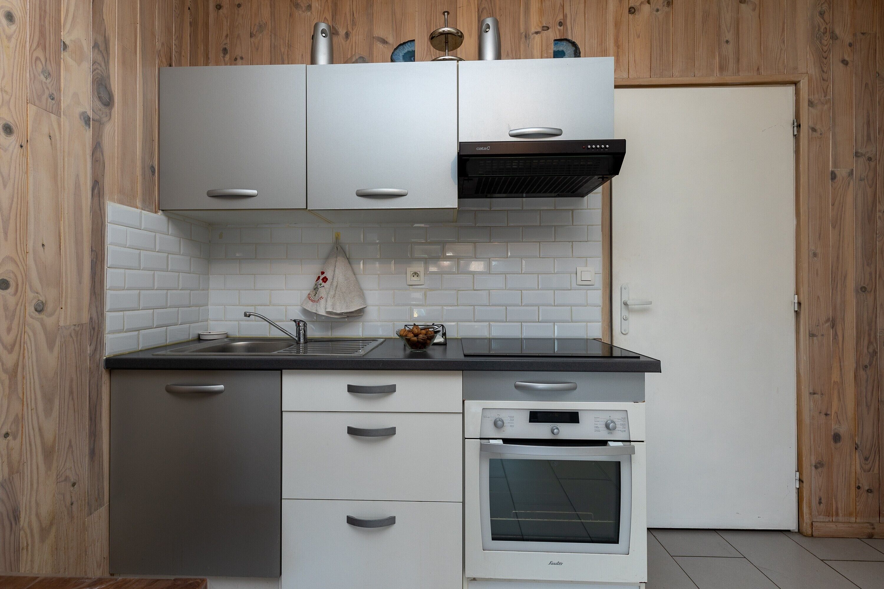 A compact kitchen with white cabinetry, a built-in oven, and a stainless steel sink.
