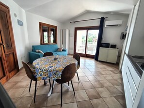 A dining area with a round table, chairs, a sofa, and a kitchen area with cabinets and a stove.